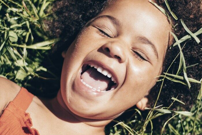 A girl lying in the grass, laughing.